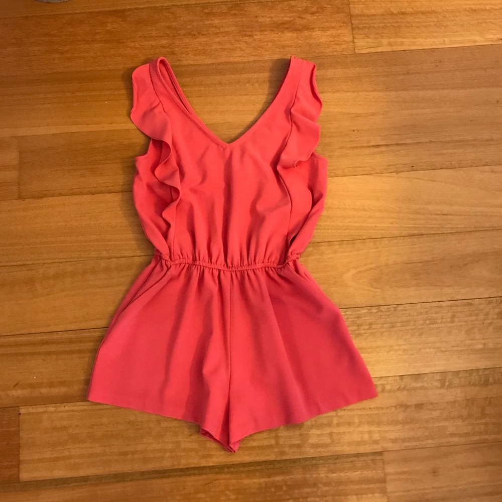 Coral colored romper with ruffles along the front